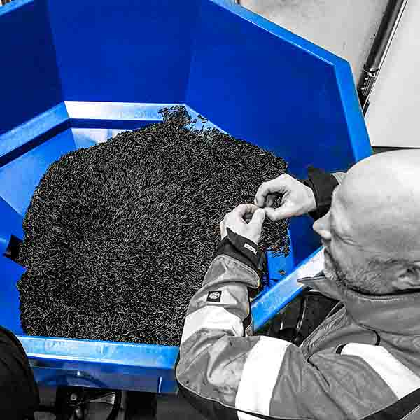 Centramec_granulathantering_materialhantering_600px En man i varselklädsel står med armarna över en oktabinkona med små plastgranulat.