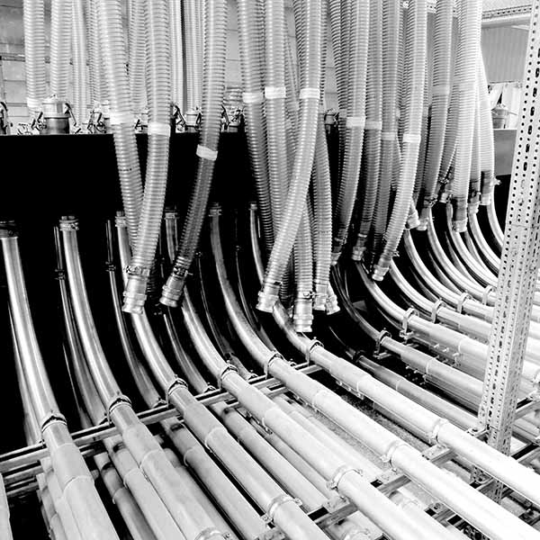 Centramec_materialhantering_pulverhanteringssytem_600px Rörledningssystem i en industriell miljö, flera slangar och kopplingar.