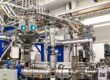 A complex industrial environment with production facility for extrusion. TSM batch mixers, control units and racks. Many pipe bends, hoses and couplings.  