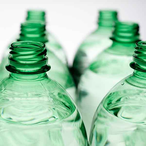 Formblåsning_centramec_600 px Flera PET-flaskor som står i två rader, med fokus på flaskornas halsar och öppningar. Flaskorna innehåller en klar vätska.